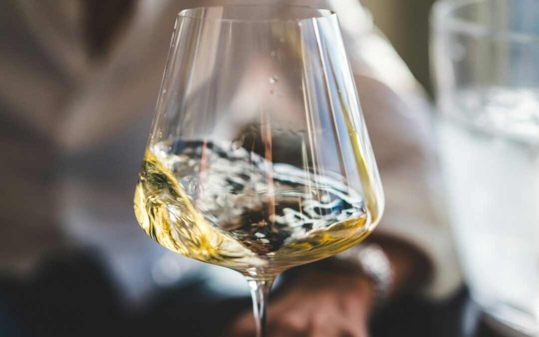 a wide-bottomed wine glass with golden-yellow wine being swirled gently.